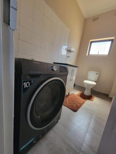 a washing machine in a bathroom with a toilet at Sable Suites C1, 1 Bed Apartments in Kabulonga in Lusaka