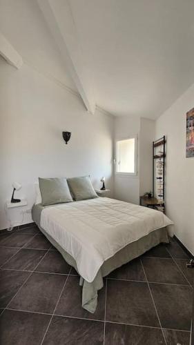 une chambre avec un grand lit dans une pièce blanche dans l'établissement Centre ville vue St Clair, à Sète