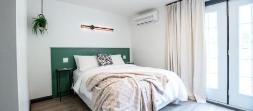 a bedroom with a bed with a green headboard and a window at Le Relais des Hautes Gorges in Saint Aime Des Lacs