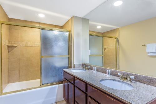 a bathroom with two sinks and a shower at Travelodge by Wyndham Suites Virginia Beach Oceanfront in Virginia Beach