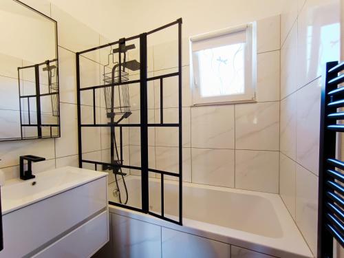 une salle de bain avec une baignoire, un lavabo et un miroir dans l'établissement Le Cocon d'Adrien, à Malijai