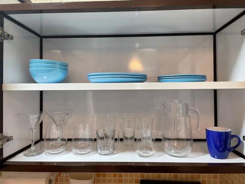 a shelf filled with glasses and blue dishes on it at Studio Apartment, close to beach and sunset views in Umm Al Quwain