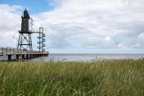 a lighthouse on a pier next to the water at Ferienhaus "Moby Dick" Mellumplate 44 in Dorum Neufeld