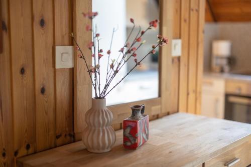 two vases sitting on a wooden table with flowers at Ferienhaus Robbenplate 11 in Dorum-Neufeld