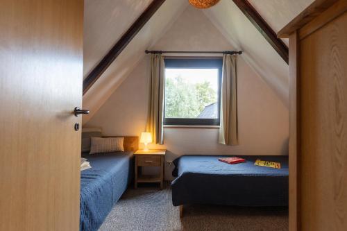 a attic room with two beds and a window at Ferienhaus Robbenplate 11 in Dorum-Neufeld