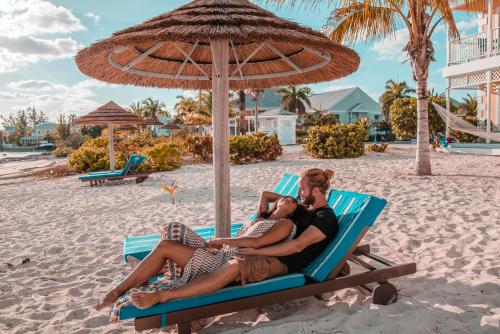 a man and woman sitting on a beach chair under an umbrella at Sandyport Beach Resort in Nassau