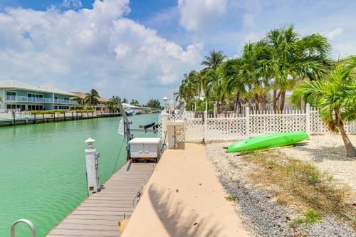 a dock with a green boat next to a body of water at Waterfront Key Colony Beach Home with Golf Cart! in Key Colony Beach