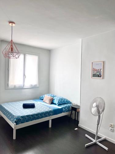 - une chambre avec un lit doté de draps bleus et d'un ventilateur dans l'établissement T3 Joliette près des terrasses du port, à Marseille