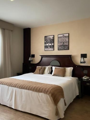 a bedroom with a large white bed with two pictures on the wall at Transamerica Executive Curitiba Batel in Curitiba