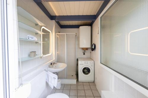 a small bathroom with a washing machine and a sink at Ferienhaus Vogelsand 08 in Dorum-Neufeld