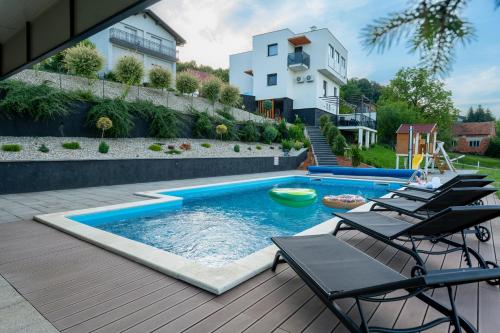 a swimming pool with chairs and a house at Apartman Zara in Krapina