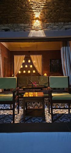 a room with two chairs and a table and a table and benches at ilika Resort, Pauri in Pauri