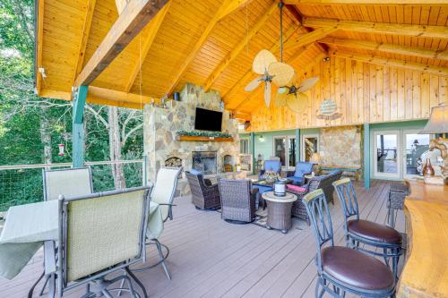 a covered deck with chairs and a fireplace at Hiawassee Home with Fire Pit and Furnished Deck! in Hiawassee