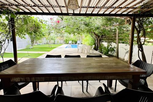 a large wooden table with chairs and a pool at Bouganville Apartments in Flecheiras