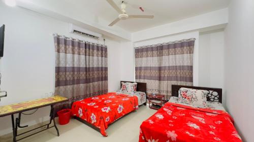 two beds in a room with red sheets at Mohammadia Restaurant & Guest House in Dhaka
