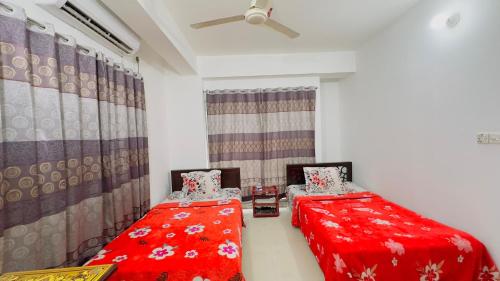 two twin beds in a room with red sheets at Mohammadia Restaurant & Guest House in Dhaka