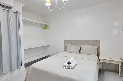 a bedroom with a white bed with two complimentary towels at Bouganville Apartments in Flecheiras