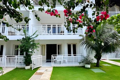 a view of the front of a white building with pink flowers at Bouganville Apartments in Flecheiras