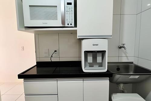 a kitchen with a microwave oven and a sink at Bouganville Apartments in Flecheiras