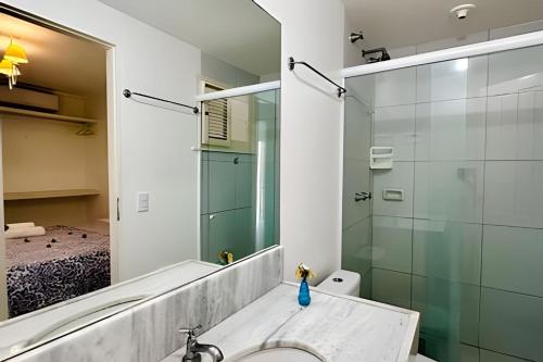 a bathroom with a shower and a sink and a mirror at Bouganville Apartments in Flecheiras