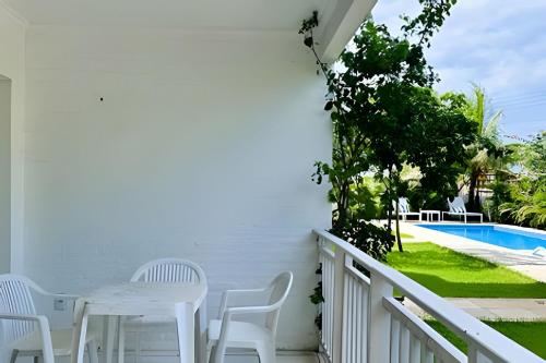 a balcony with white chairs and a table and a pool at Bouganville Apartments in Flecheiras