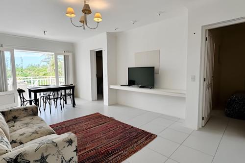a living room with a couch and a tv and a table at Bouganville Apartments in Flecheiras