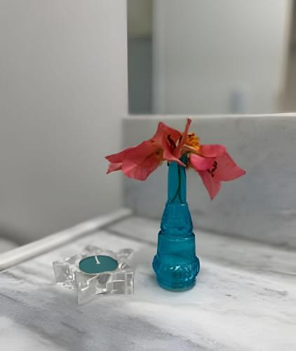 a blue vase with a flower in it on a counter at Bouganville Apartments in Flecheiras