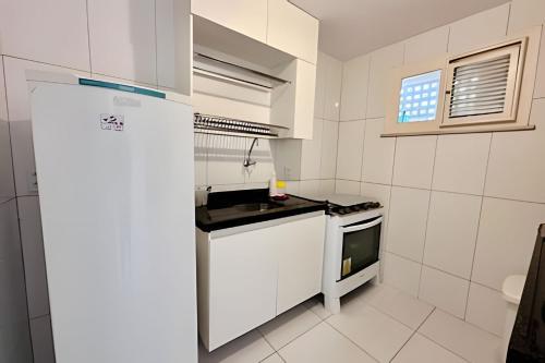 a white kitchen with a refrigerator and a stove at Bouganville Apartments in Flecheiras