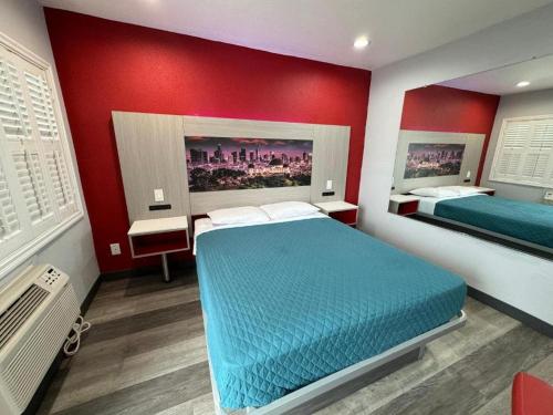 a bedroom with two beds and a red wall at Playa Inn Motel - Long Beach, LA in Long Beach