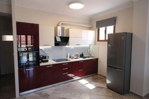a kitchen with brown cabinets and a black refrigerator at Central Apartments in Kardamili