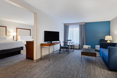 a hotel room with a bed and a tv and a couch at Holiday Inn Express & Suites Cincinnati Riverfront by IHG in Covington