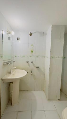 a white bathroom with a sink and a shower at Mohammadia Restaurant & Guest House in Dhaka