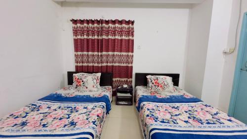 two beds in a room with a curtain at Mohammadia Restaurant & Guest House in Dhaka