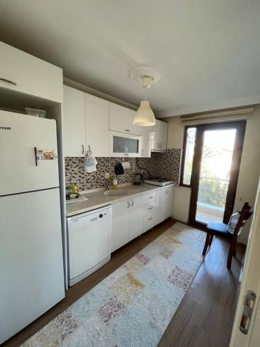 Una cocina con gabinetes blancos y un refrigerador. en Haliç Apartmani Inn, en Yalova