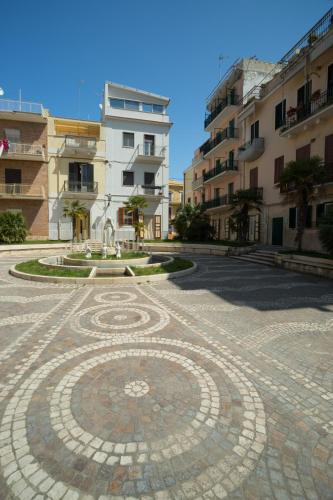 a tiled courtyard with a fountain in front of some buildings at ControVento Rooms in Margherita di Savoia