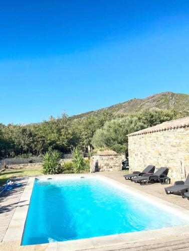 une piscine avec deux chaises et une maison dans l'établissement Villabergerie En Pierre Du Pays, à Barbaggio