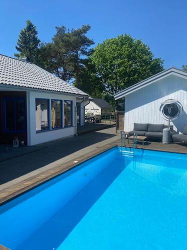 a large blue swimming pool next to a house at Villa Valencia Falkenberg in Falkenberg