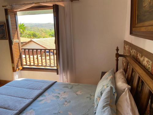 a bedroom with a bed and a large window at Casarão Coimbra Pousada Colonial in Pirenópolis