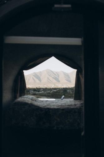 ein Vogel, der in einem Fenster mit Bergen im Hintergrund steht in der Unterkunft El Cubil en Potrero Chico in Hidalgo