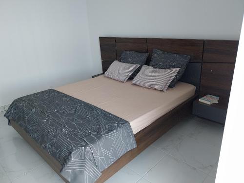 - un lit avec une tête de lit en bois et des oreillers dans l'établissement Le CosY Appart 43M2 Clim Vue Mer Golfe de Saint Tropez, à Cavalaire-sur-Mer