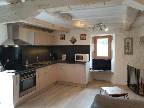 une cuisine avec des armoires blanches et un four à plaques de cuisson dans l'établissement Maison en pierre de hameau, à Aizac