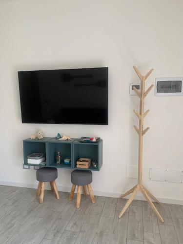 a living room with two chairs and a tv on a wall at Appartamento Massimo in Nettuno