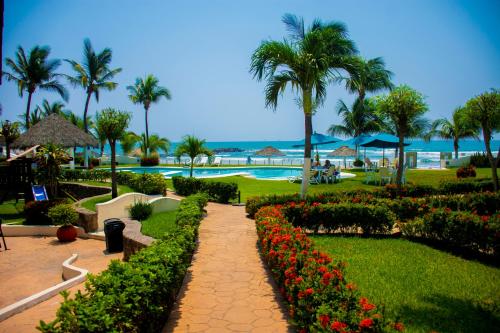 a resort with a garden with flowers and a swimming pool at Playa Caracol Hotel & Spa in Veracruz