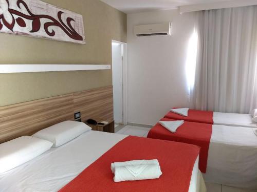 a hotel room with two beds with red and white sheets at Pousada Aquarela Do Brasil in Maceió