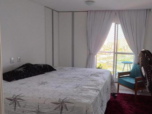 a bedroom with a bed and a chair and a window at Quartos - Cíntia in Fortaleza