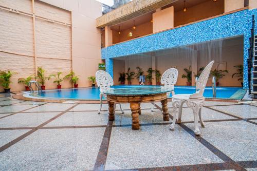 a table and two chairs in front of a pool at The Marwar Hotel & Gardens in Jodhpur