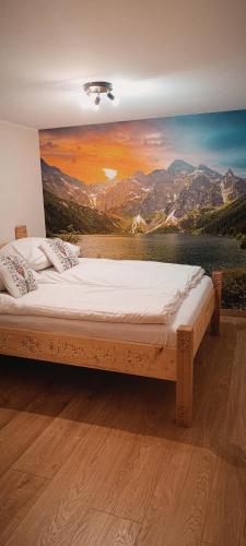 a bed in a room with a painting on the wall at Apartament Olczański Chëcz in Zakopane