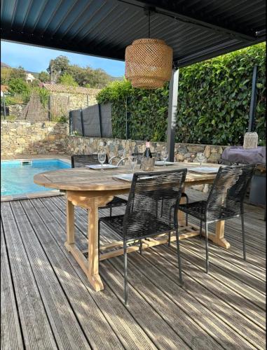 une table et des chaises en bois sur une terrasse en bois dans l'établissement Villa De Charme T3 Saint Florent, à Barbaggio