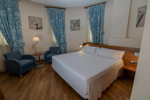 a hotel room with a bed and a blue chair at Hotel Mieres del Camino in Mieres