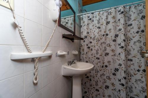Un baño con lavabo y cortina de ducha. en Cabañas Rayun, en Villa Ventana
